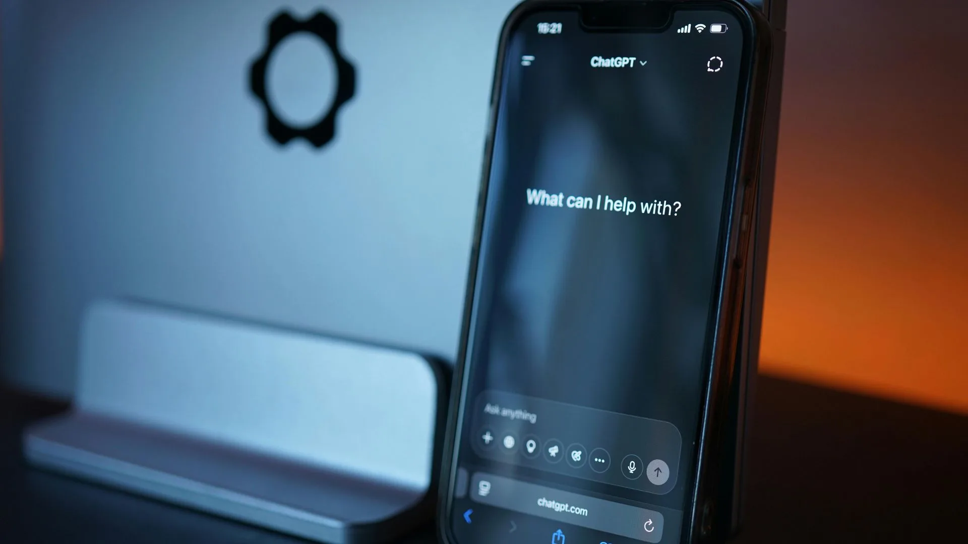 Smartphone displaying ChatGPT interface beside a laptop